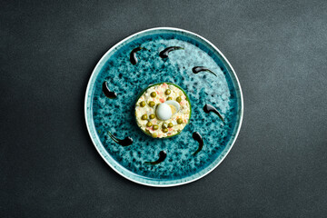 Olivier salad. Salad of green peas, boiled vegetables and mayonnaise. Close-up, gray background.