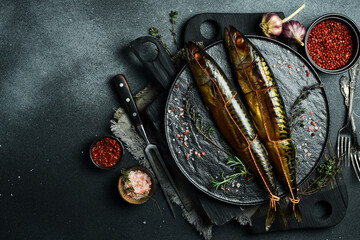 Appetizing smoked fish on kitchen board. Smoked mackerel. On a black slate plate.