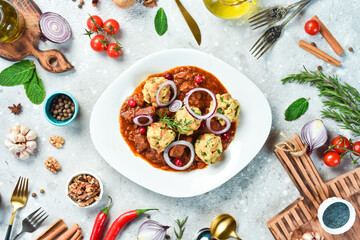 Veal baked in tomato sauce with meatballs. On a white plate. On a gray stone background. Restaurant menu.