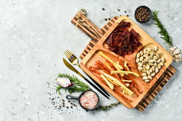 Snacks for beer. Pistachios, cheese, sausages and dried meat. On a wooden plate. Rustic style.