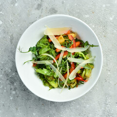 Fresh vegetable salad with parmesan, in a white plate. Rustic style.