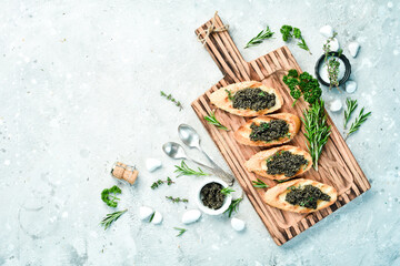 Caviar sandwiches and caviar in a bowl. Premium quality. Luxury snacks. On a gray stone background. Rustic style.