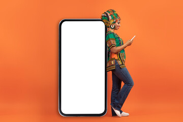 Stylish african woman in bright costume leaning on huge phone