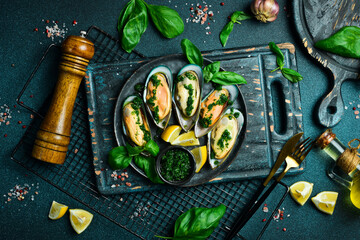 Close up of delicious steamed mussels with basil and garlic. On a black stone plate. Seafood.