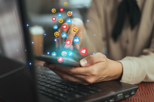 Hands holding and typing smartphone to communicate with emoji social icon. Online social communication chat on mobile phone with emoticon graphic.