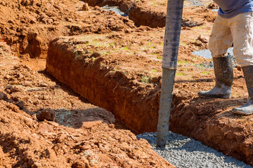 Pouring cement concrete with assistance of an automatic pump to lay building foundation is...