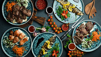 A set of meat dishes: shish kebab, kebab, steak, fish. On a black background. Top view. Free space for text.