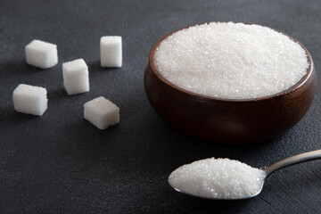 Cube sugar and granulated sugar on black background