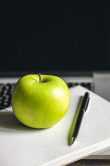 Apple near laptop at workplace, healthy snack.