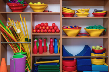 Sport equipment located in wooden rack inside of recreation center front view. Children sport...