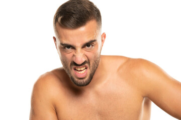 Fototapeta premium portrait of young angry shirtless man with beard, screaming on a white background