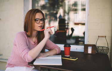 Thoughtful woman sitting at table with notebook in cafe