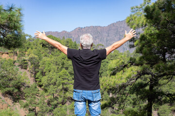 Rear View of Senior Man Enjoying Trekking Day on Mountain Standing with Open Arms Admiring the Beautiful of Nature - Freedom, Sport, Healthy Lifestyle Concept