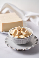 Tofu made with soybeans, sliced in cubes and served on a plate.