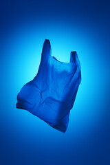 one blue plastic bag on blue background, color, vertical 