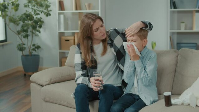 Caring Mother Embracing Sick Her Little Son. Son Using Paper Tissue, Suffering From Runny Nose Sinusitis Nasal Infectious Disease, Feeling Uncomfortable at Home. First Grippe Symptoms.