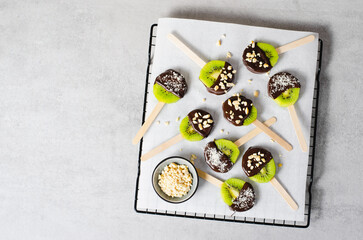 Kiwi Coved In Chocolate with Shredded Coconut and Nuts on a Stick, Healthy Snack on Bright...