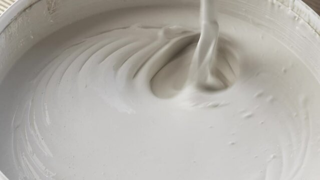 Mixing white paint in bucket, Closeup