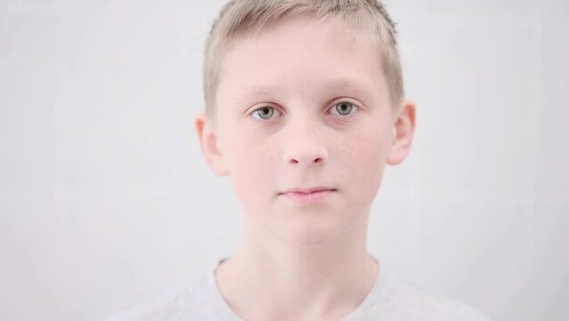portrait of a teenager boy close-up looks seriously at the camera. caucasian boy with blond hair and beautiful eyes. white background. Beautiful child, Schoolboy. Human emotions