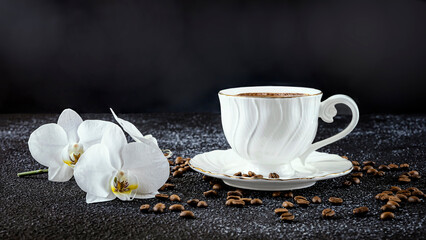White cup of coffee, white orchid flowers, coffee beans and white candles. Romantic composition on a black background