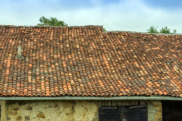 Fragment of an old stone farm barn with roof tiles