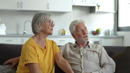 Dreamy middle aged senior loving retired family couple looking in distance, planning common future or recollecting memories, enjoying peaceful moment relaxing together on cozy sofa in living room
 - Powered by Adobe