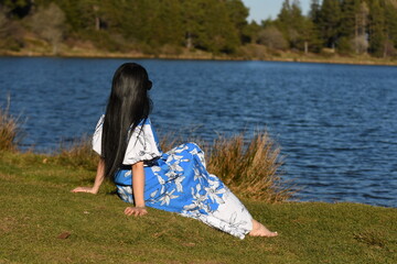 Une femme assise au bord d'un lac en été