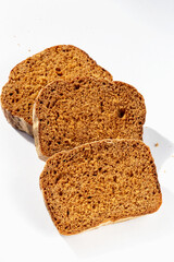 Three slices of fresh dark bread on white background in sunlight