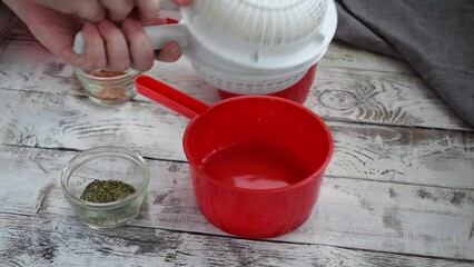 Making homemade adyghe cheese in the cheese making mold. Turning the hot product for further pressing and sprinkling the other side with dried herbs and salt 