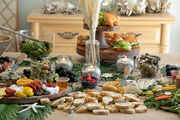 Beautiful charcuterie table set up for lunch with meats, cheeses, sandwiches, and vegetables.