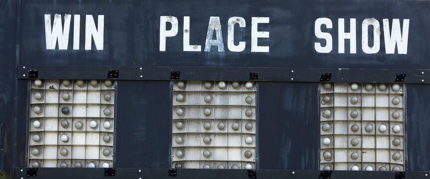 Weathered horse racing sign saying, win, place, show.
