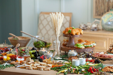 Beautiful charcuterie table set up for lunch with meats, cheeses, sandwiches, and vegetables.