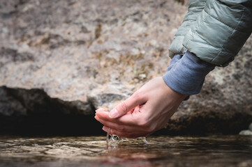 Close-up of hands scooping clean water. A man draws raw water from the lake. The concept of...