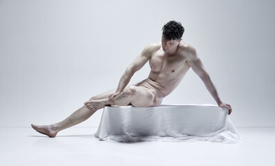 Portrait of handsome mature man with relief muscular body posing in statue pose against grey studio background. Like antique sculpture. Concept of male body aesthetics, men's beauty, inspiration, art