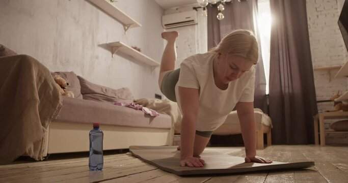 Tired young overweight lady doing buttock exercise on mat at home