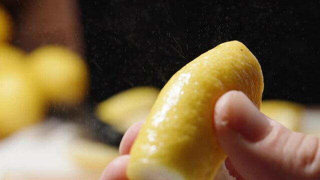 Lemon zest spray. A man's hand squeezes lemon zest in slow motion.