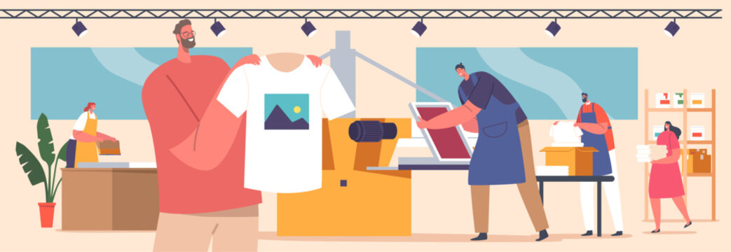 Silk Screen Printing Studio With Workers Applying Ink Onto A T-shirts Through A Stencil. Creating Design Process