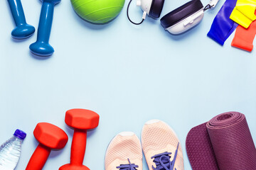Fitness and workout equipment , sneakers, headphones and bottle of water on light blue background with copy space for your design. healthy lifestyle concept.
