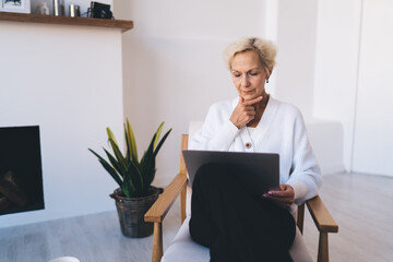 Thoughtful female freelancer with computer in living room