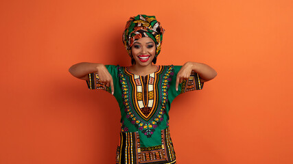 Beautiful black woman in african clothing pointing at herself