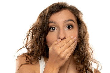 young beautiful shocked  girl covering her mouth with her hands on a white studio background