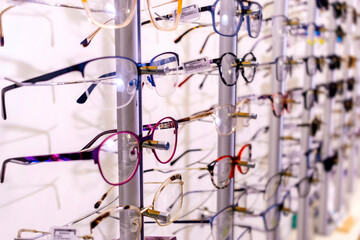 In optician shop. Different glasses for sale in wall rack.