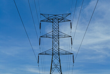 Electrical tower against a blue cloudy sky