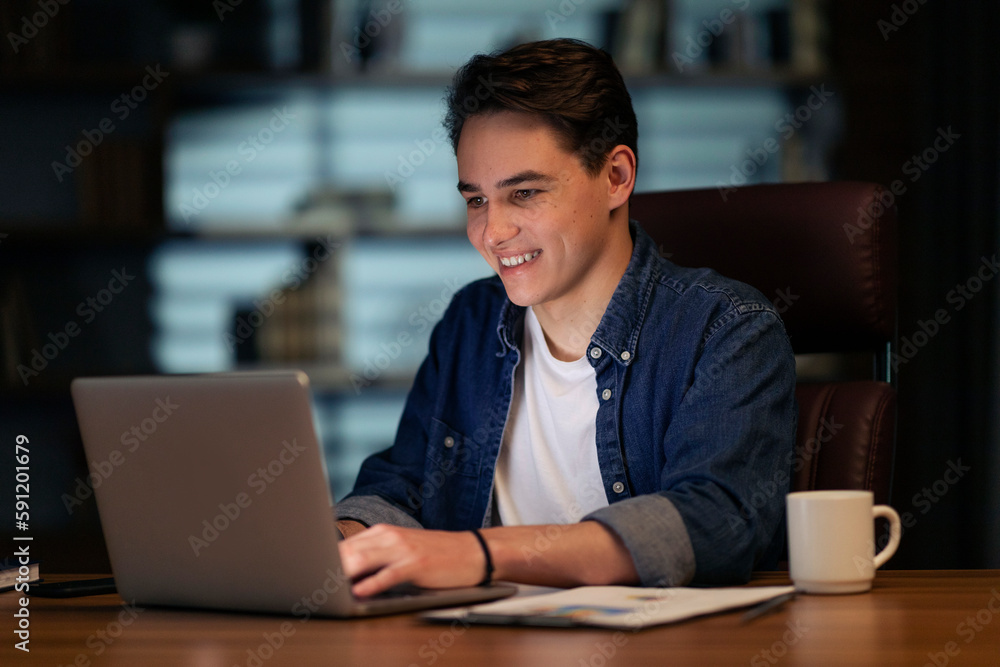 Poster cheerful young man startuper typing on pc keyboard and smiling