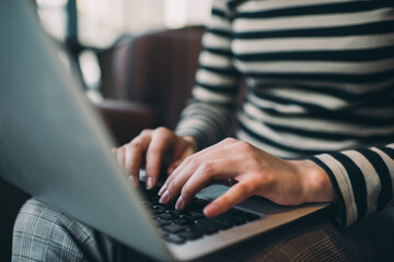 Crop female freelancer typing text on laptop