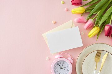 Mother's Day concept. Top view photo of plate cutlery knife fork envelope with postcard alarm clock small hearts baubles and bunch of colorful tulips on pastel pink background with copyspace