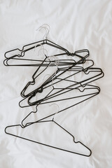 Fototapeta premium Lots of hangers on white linen cloth. Minimalist fashion, wardrobe, clothes concept. Flat lay, top view