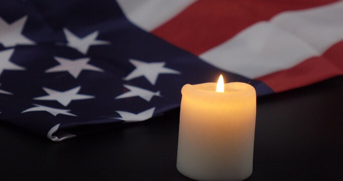 A burning candle on the background of the flag of the United States. Background of grief, memories or celebrations