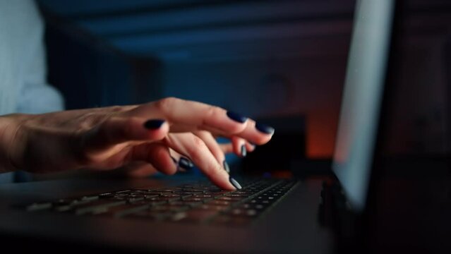 Close up of female hands typing in notebook, searching information in a dark room. Black keyboard, bright screen in the lens. The fingers print fast. High quality 4k footage