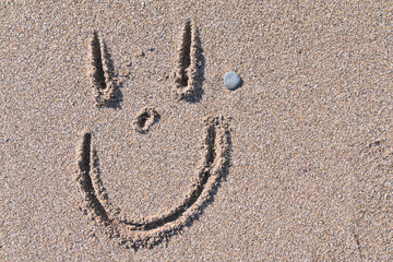 Cara sonriente dibujada sobre la arena de la playa - obrazy, fototapety, plakaty